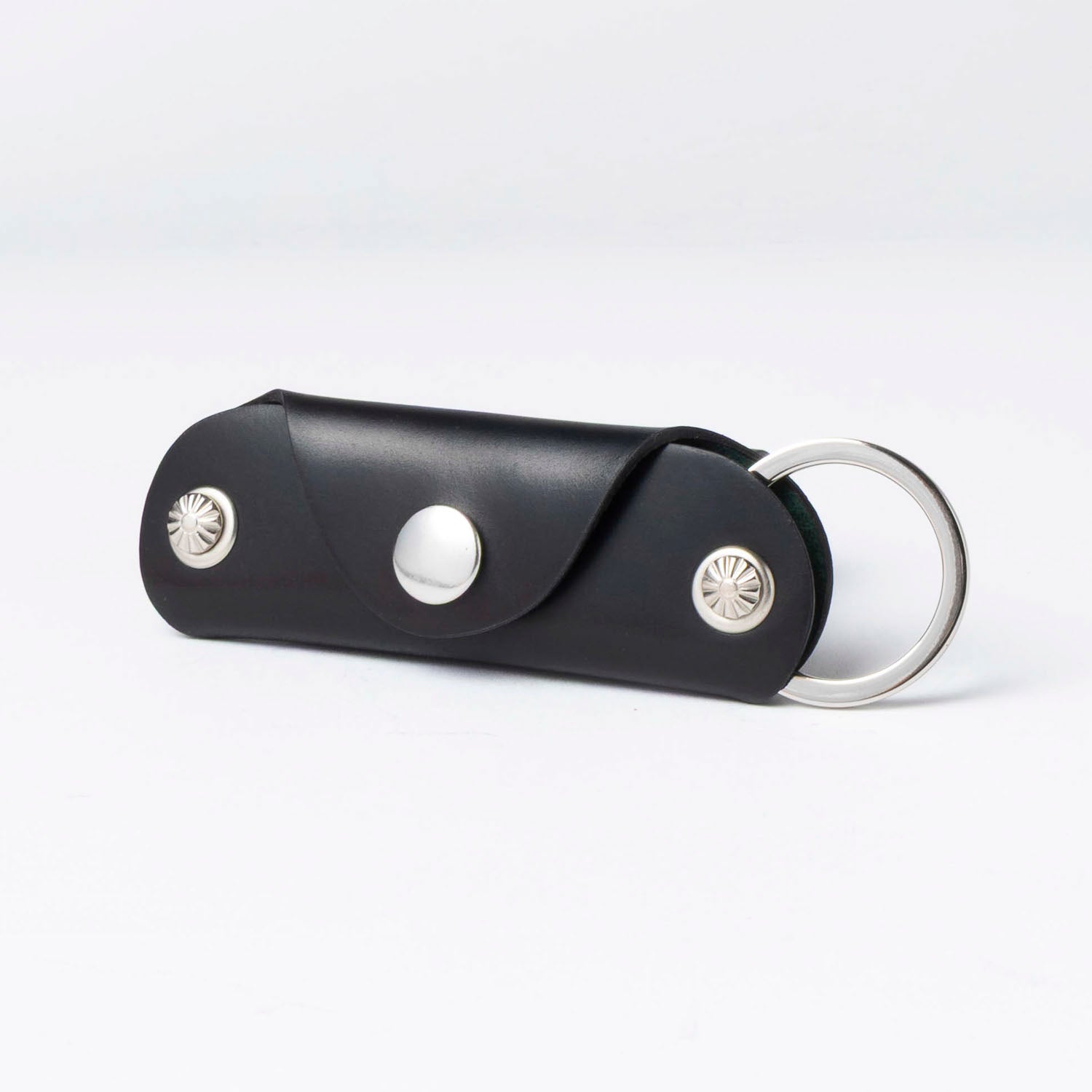 Black leather keychain with silver accents on a white background