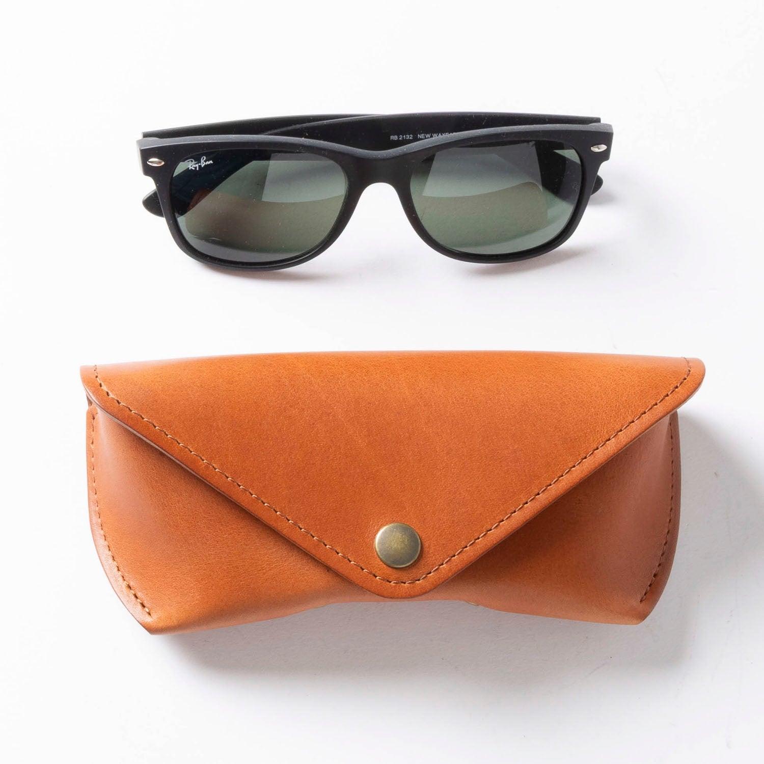 Black sunglasses with a brown leather case on a white background