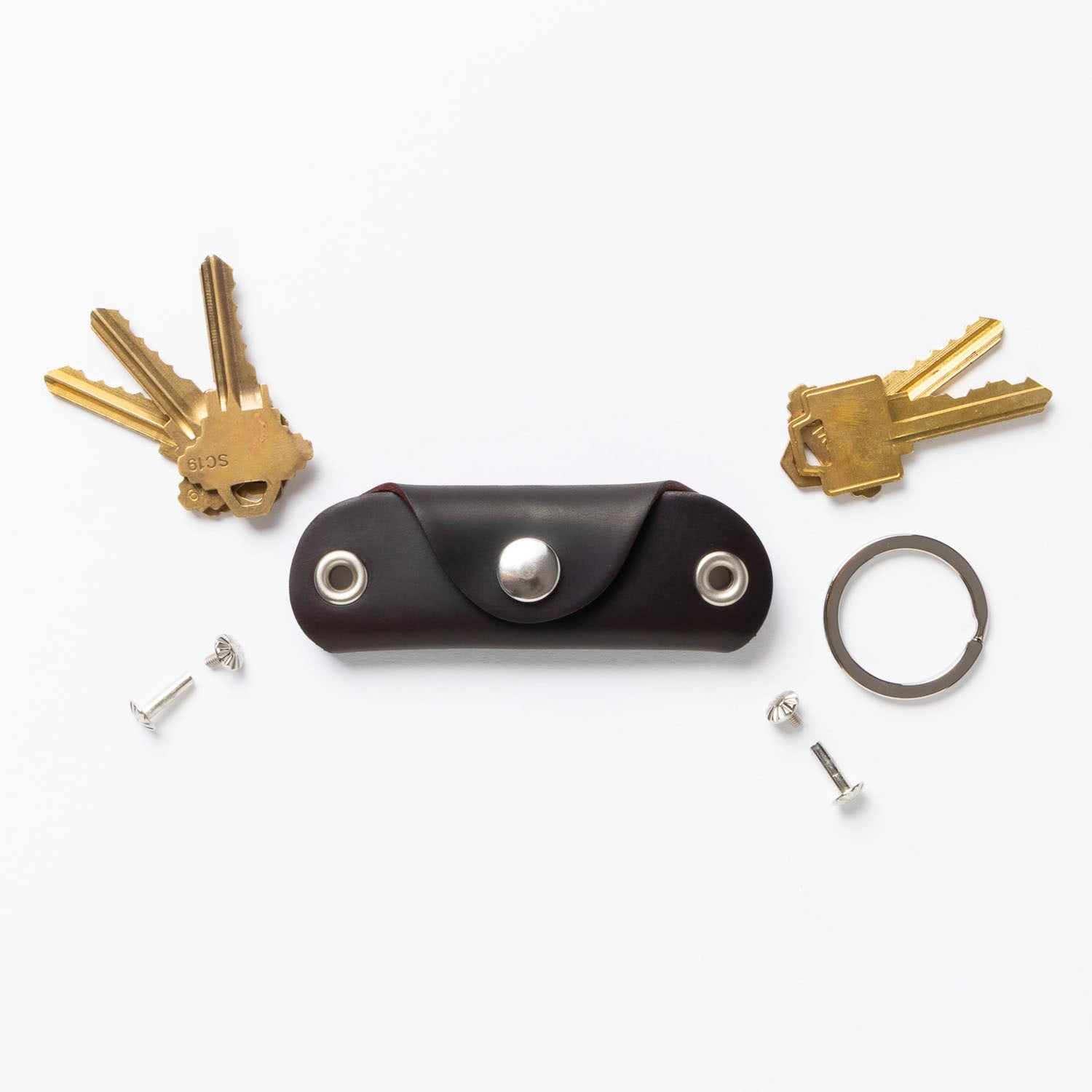 Brown leather key organizer with keys and accessories on a white background
