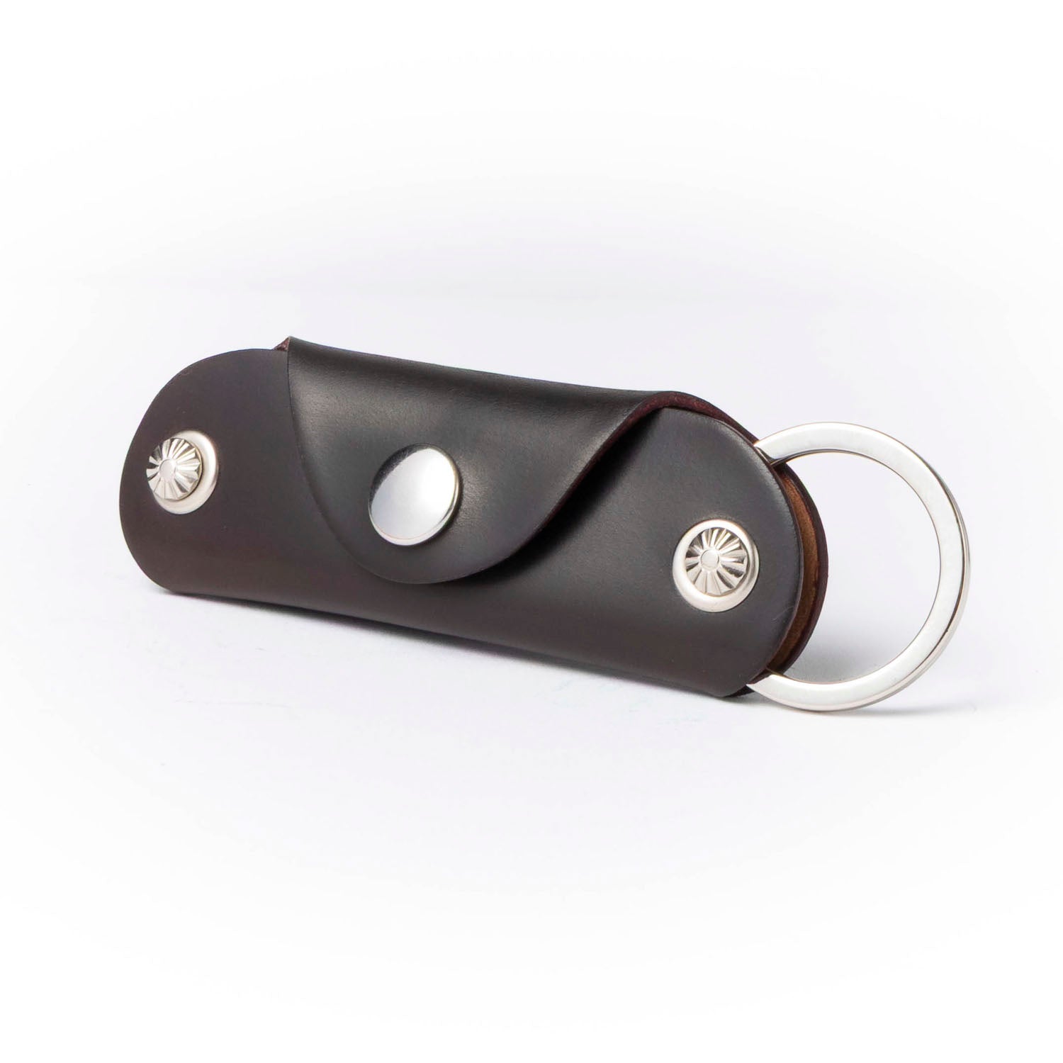 Brown leather key case with silver accents on a white background