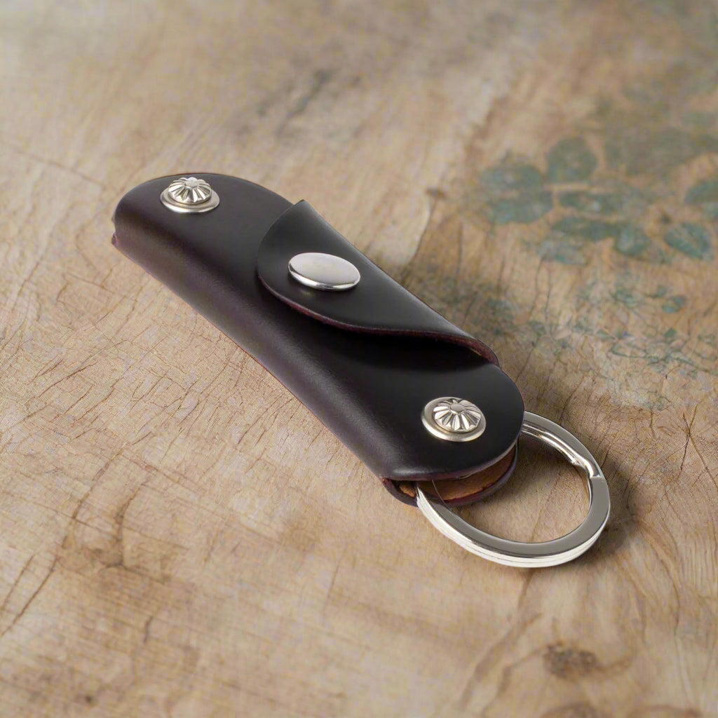 Brown leather key fob with silver accents on a white background