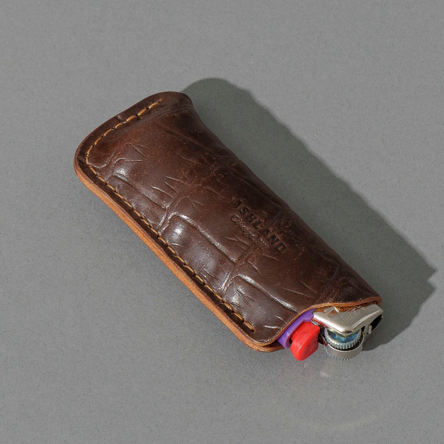 One-Off BIC Lighter and Sheath in Gator Cigar Shell Cordovan, angled view lying flat