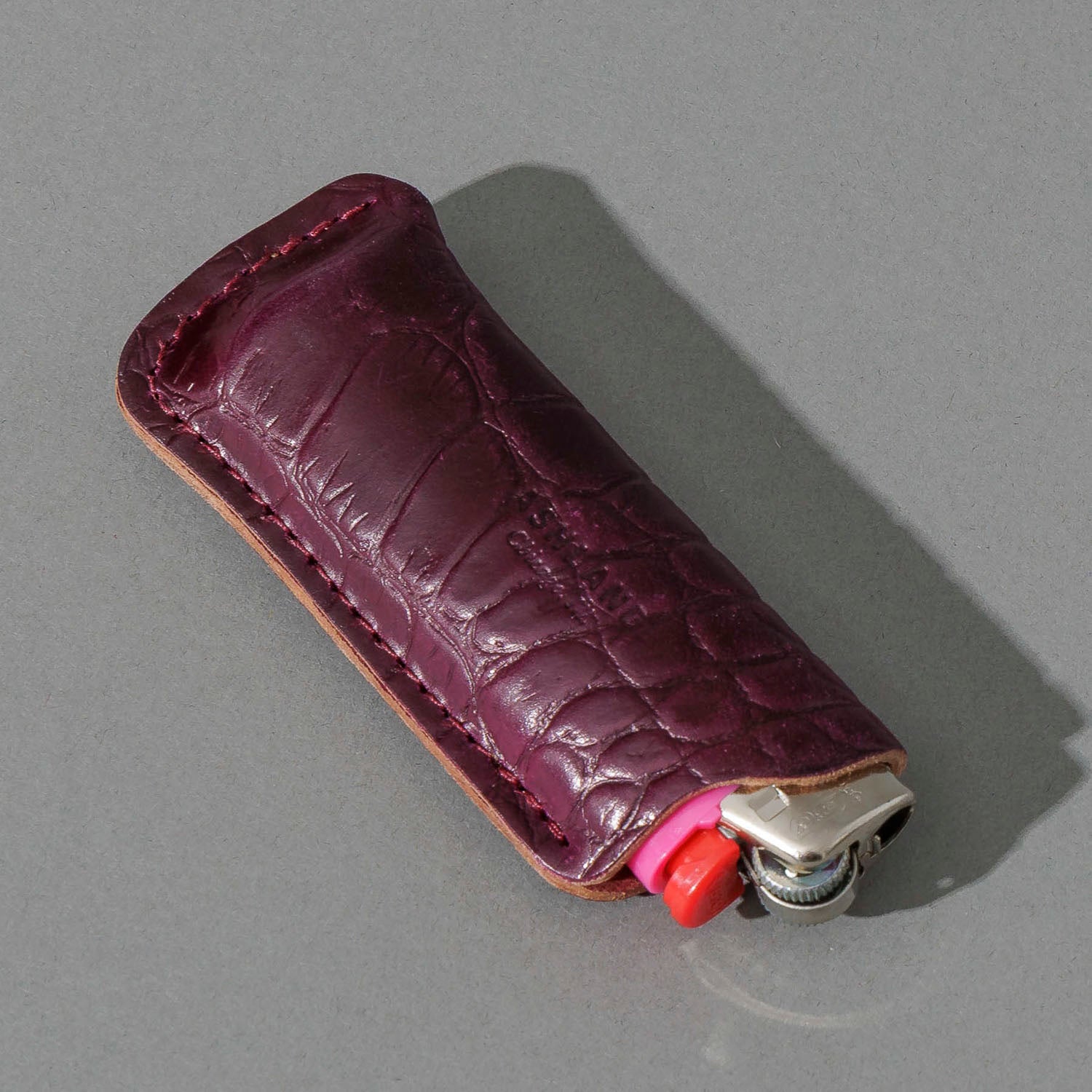 One-Off BIC Lighter and Sheath in Gator Ultraviolet Shell Cordovan, angled view lying flat