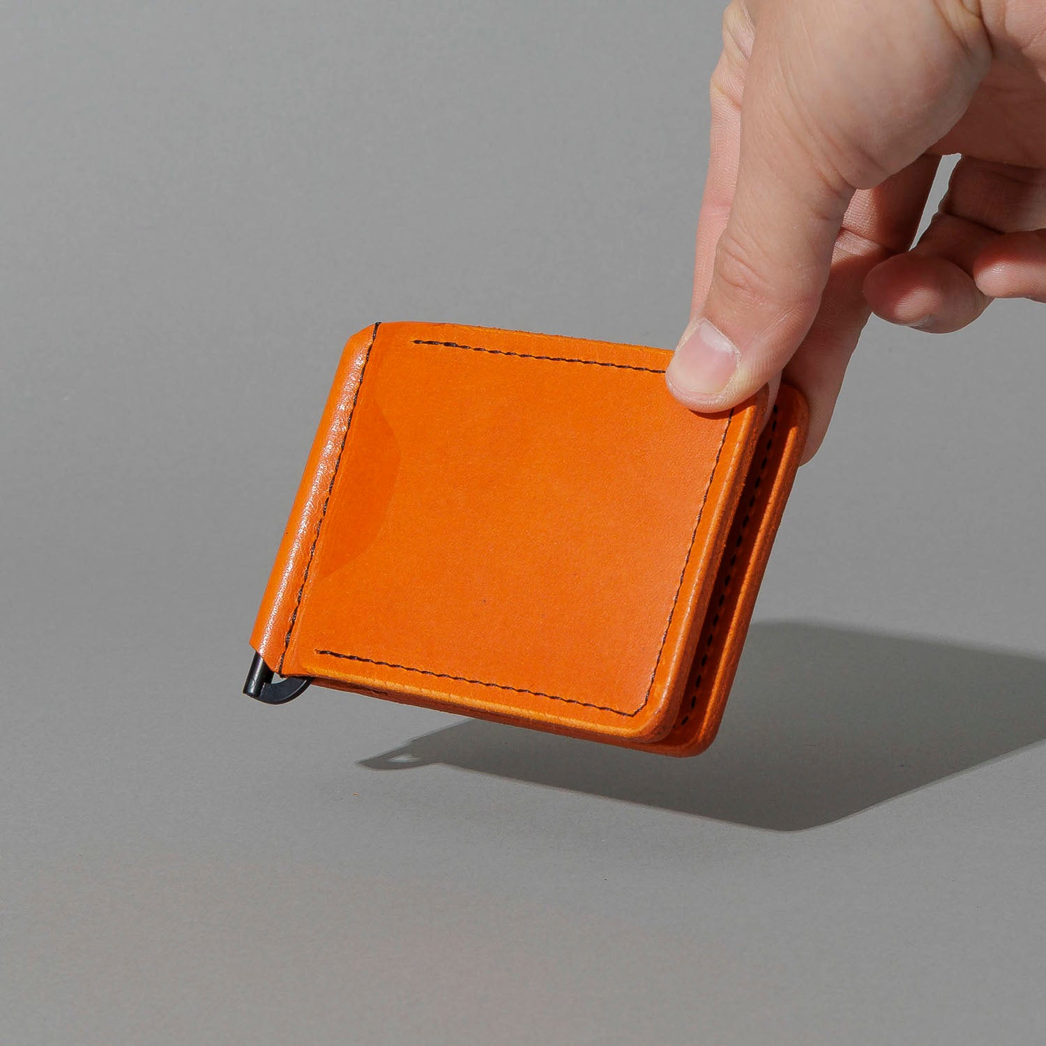 Capone Money Clip in Orange Latigo, held in hand, shot 1