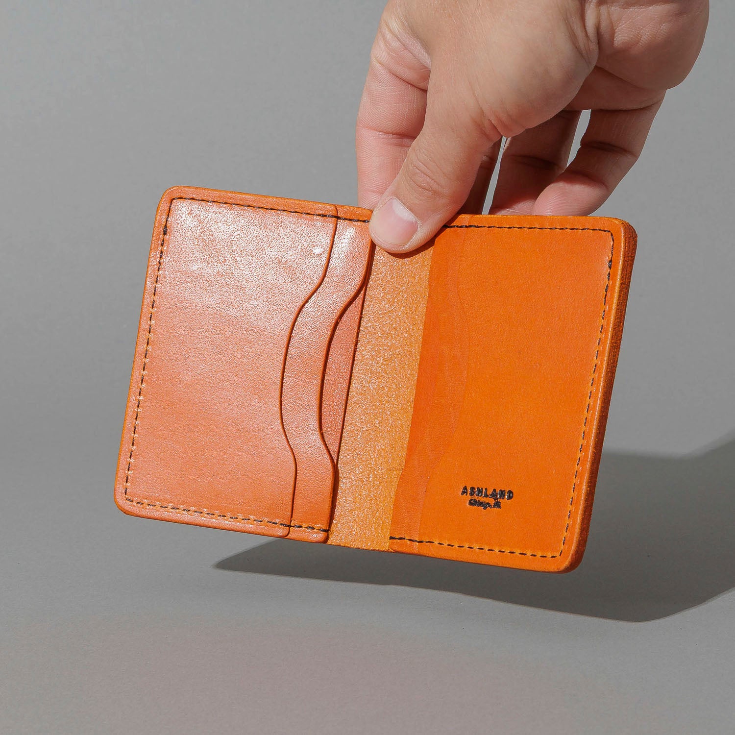 One-Off Six-Slot Bugs Moran Prototype in Orange Latigo, Skip Stitch, held open in hand, shot 2