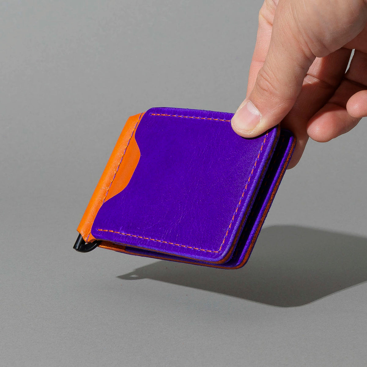 One-Off Capone Money Clip in Violet on Orange Latigo, held in hand, shot 2