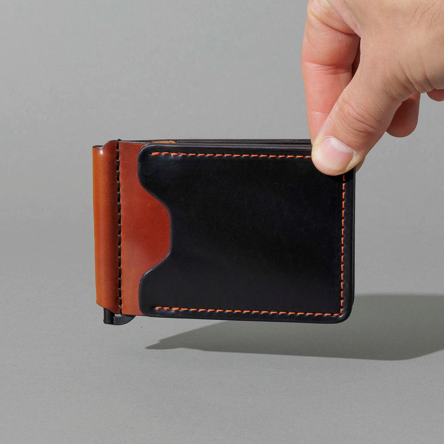 One-Off Capone Money Clip in Black on Blood Orange Shell Cordovan, held in hand