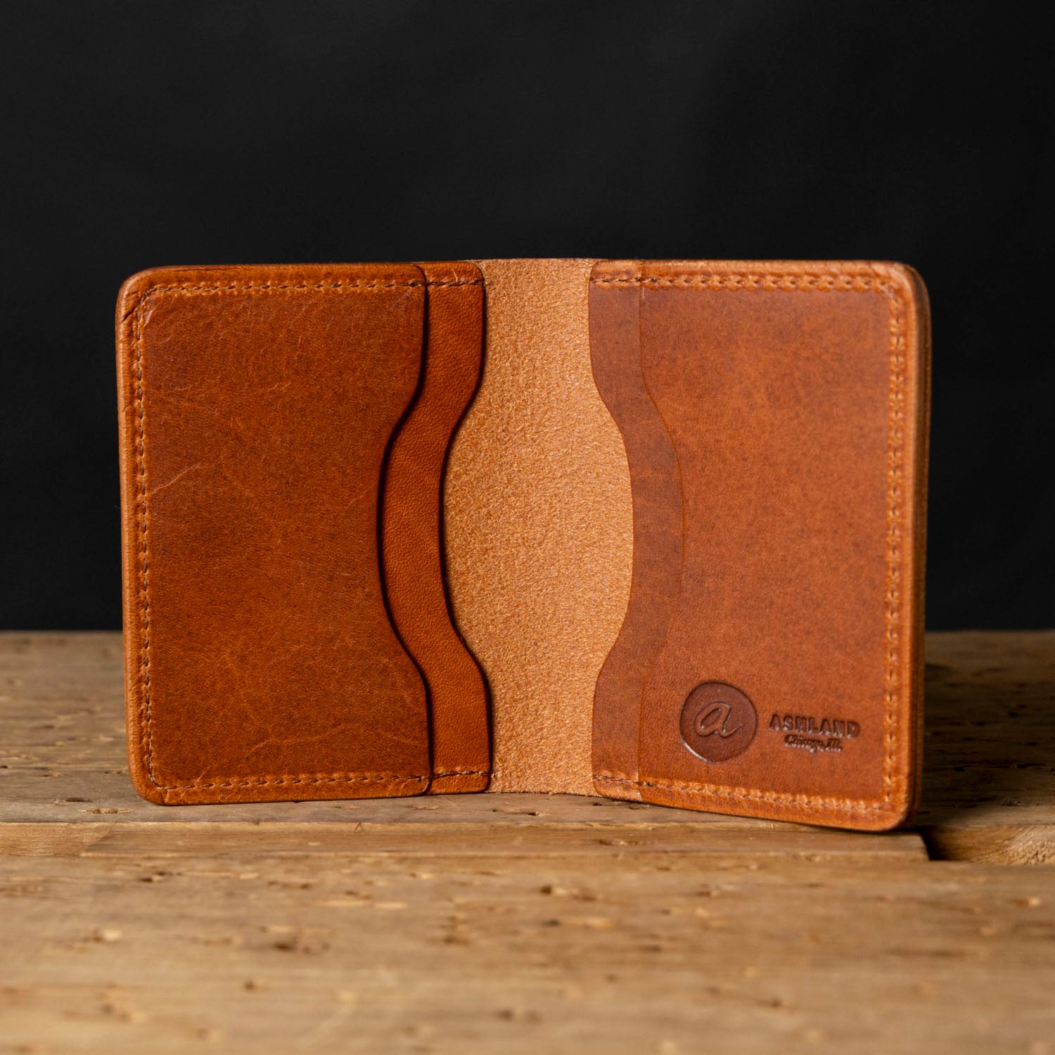 Brown leather wallet on a wooden surface with a dark background