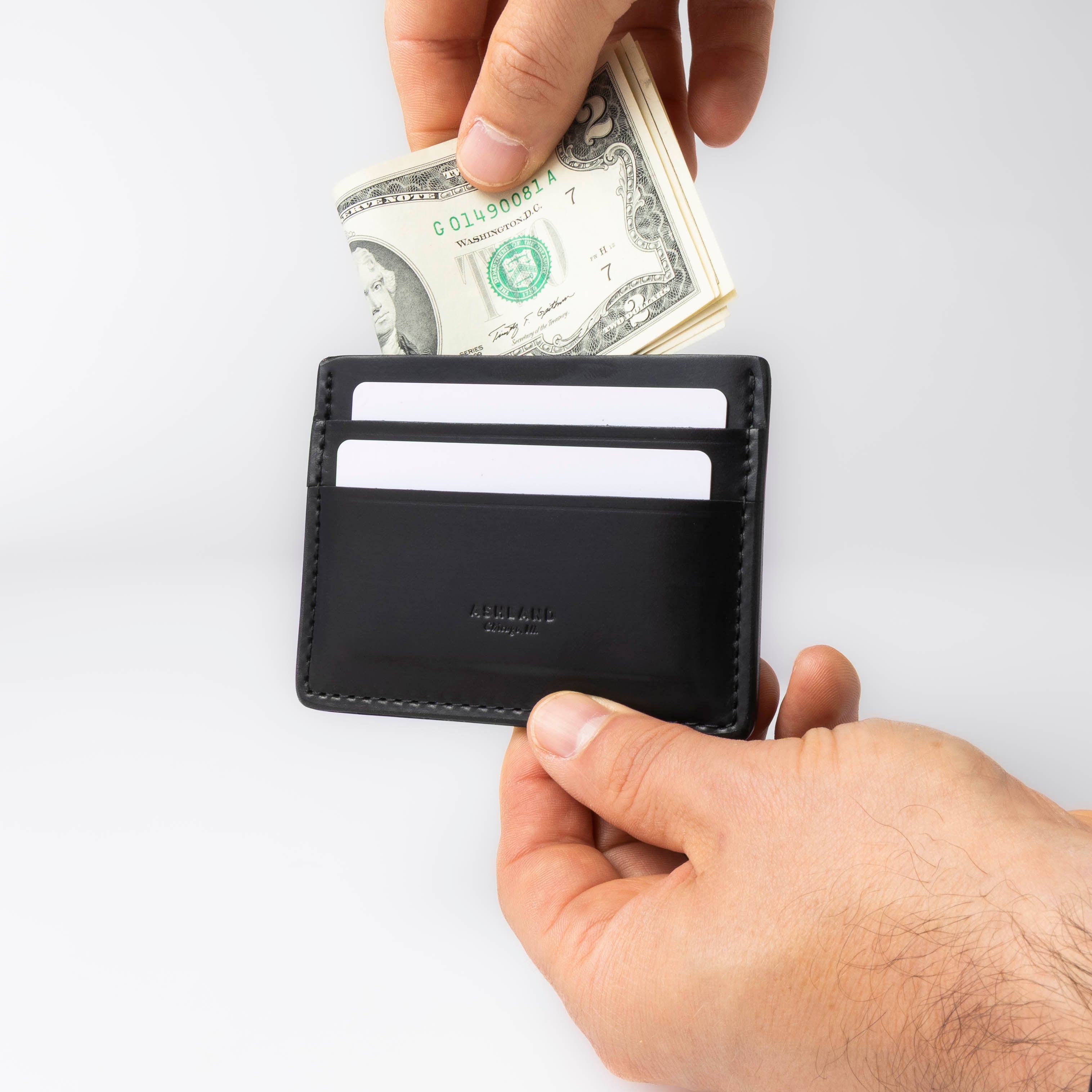 Person inserting money into a black wallet on a white background