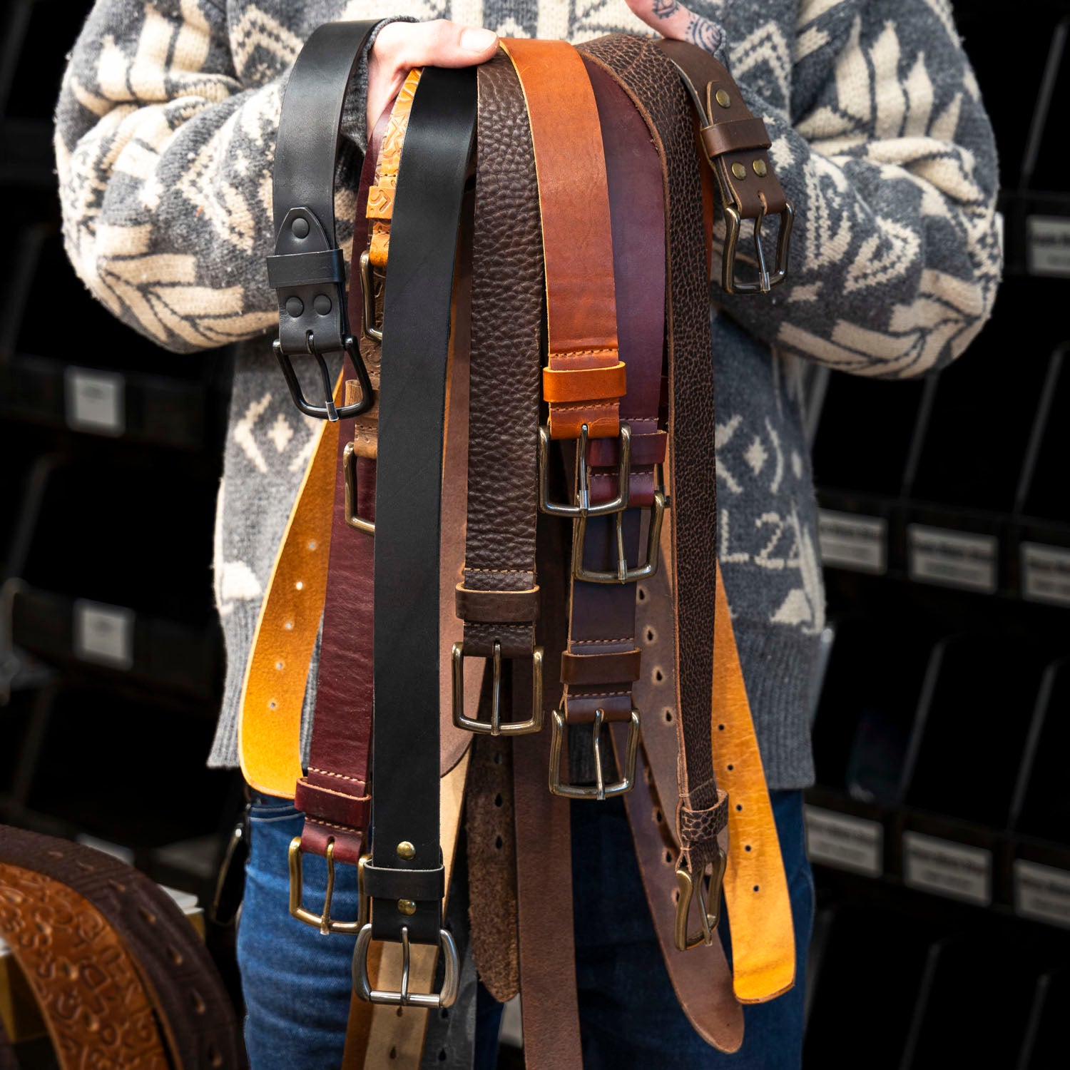 a collection of Ashland Leather belts b-grade men's in a model's hands