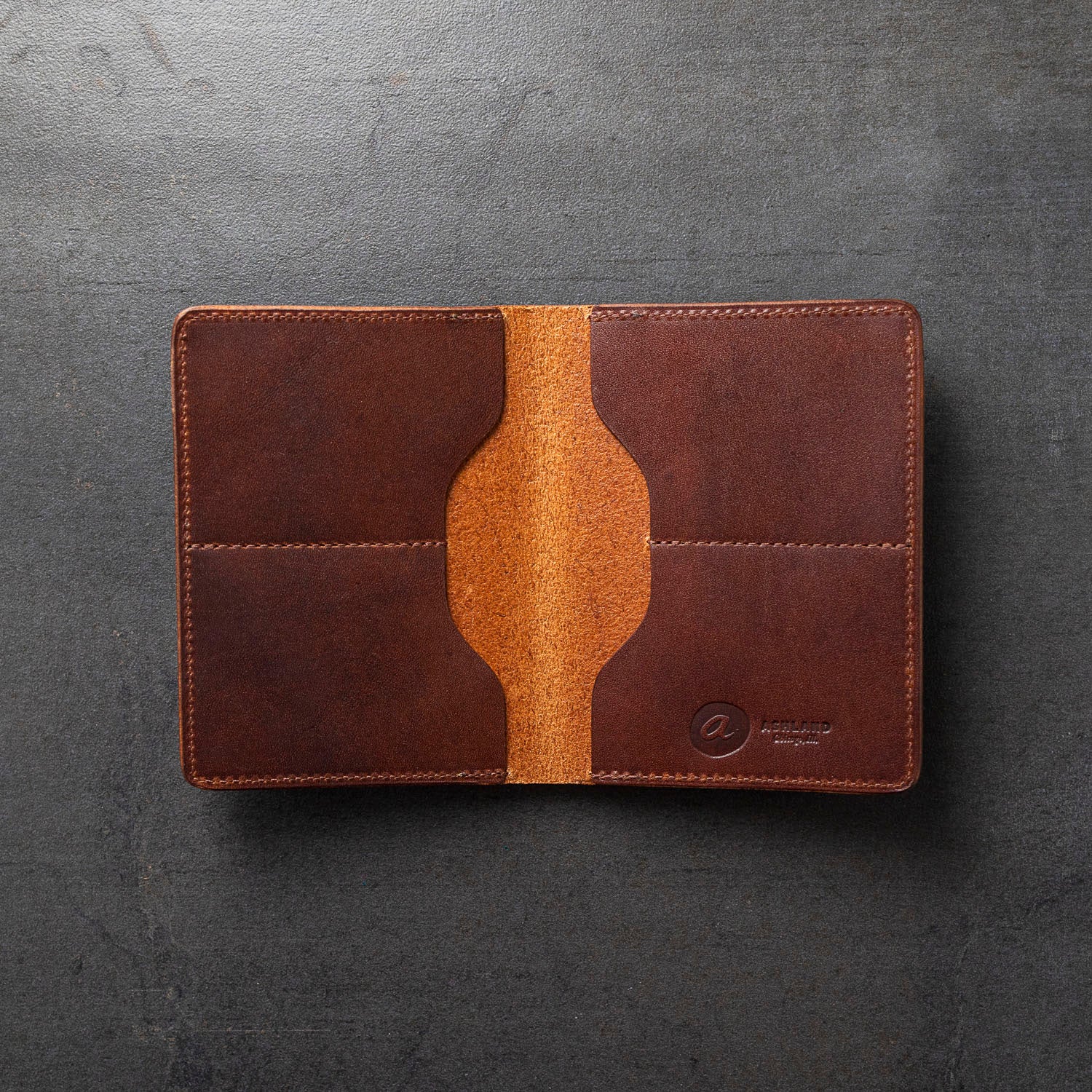 A brown leather bifold wallet, partially opened, showing the interior with card slots and a bill compartment.
