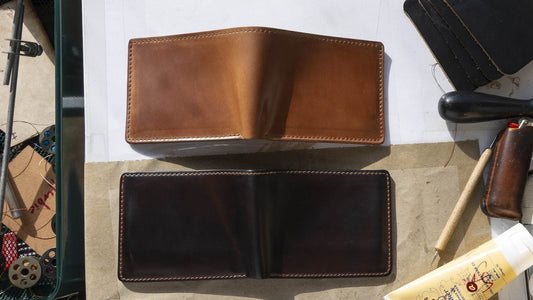 A newer light tan Horween® Shell Cordovan bifold above an aged, deeply darkened shell cordovan bifold on the Ashland Leather workbench