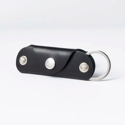 Black leather keychain with silver accents on a white background