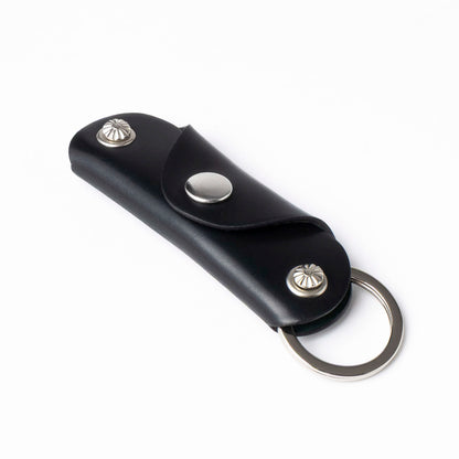 Black leather key fob with silver accents on a white background