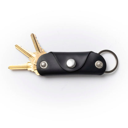Black leather key organizer with keys on a white background