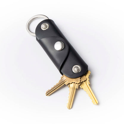 Black leather keychain with gold keys on a white background