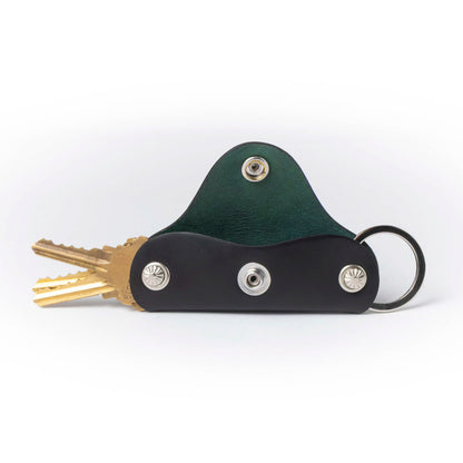 Green and black leather key holder with keys on a white background
