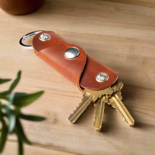 Brown leather key holder with brass keys on a white background