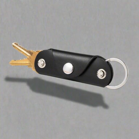 Black leather key organizer with keys on a white background