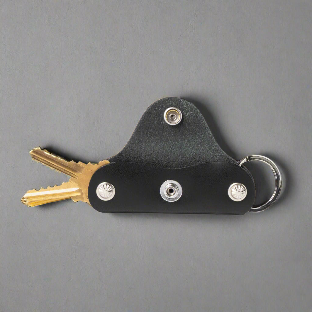 Black leather key holder with keys on a white background