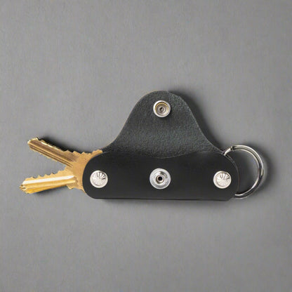 Black leather key holder with keys on a white background