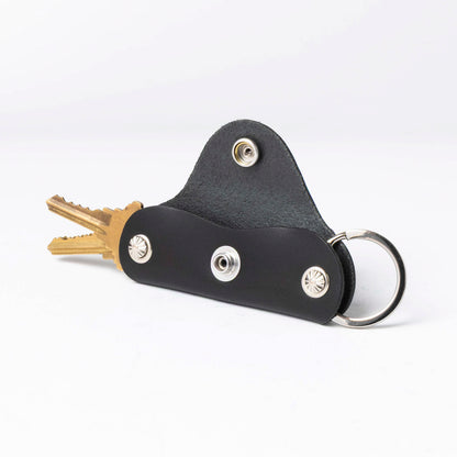 Black leather key holder with keys on a white background