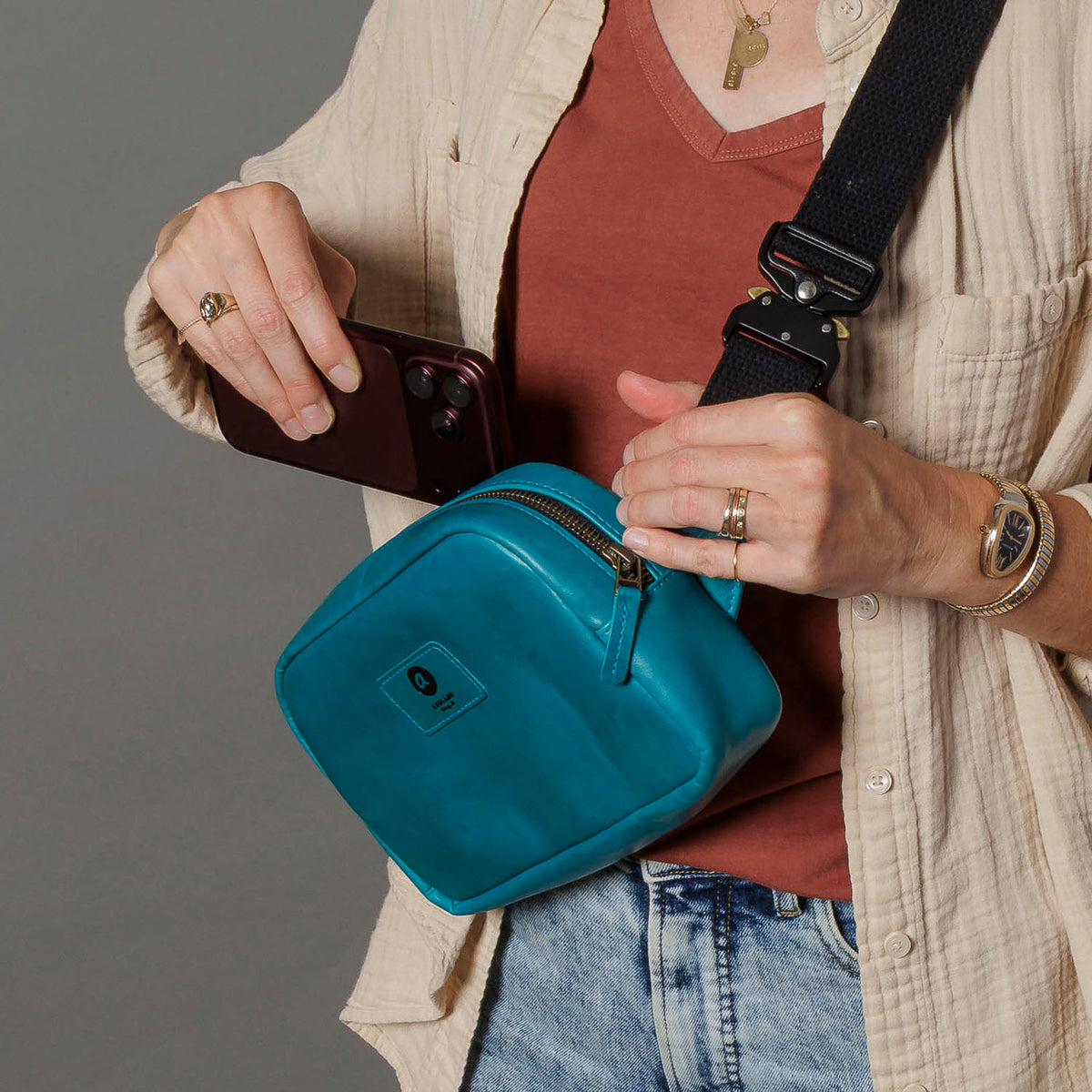 One-off Sling Bag in Horween® Teal Latigo leather, phone going into the exterior back pocket while worn