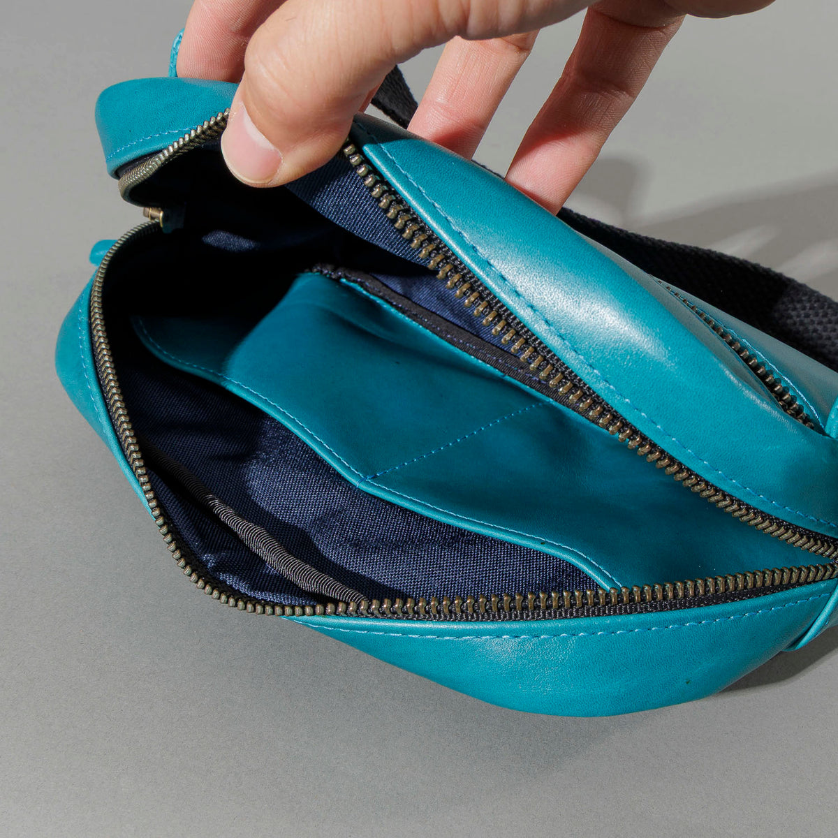 One-off Sling Bag in Horween® Teal Latigo leather, unzipped, showing the interior lining