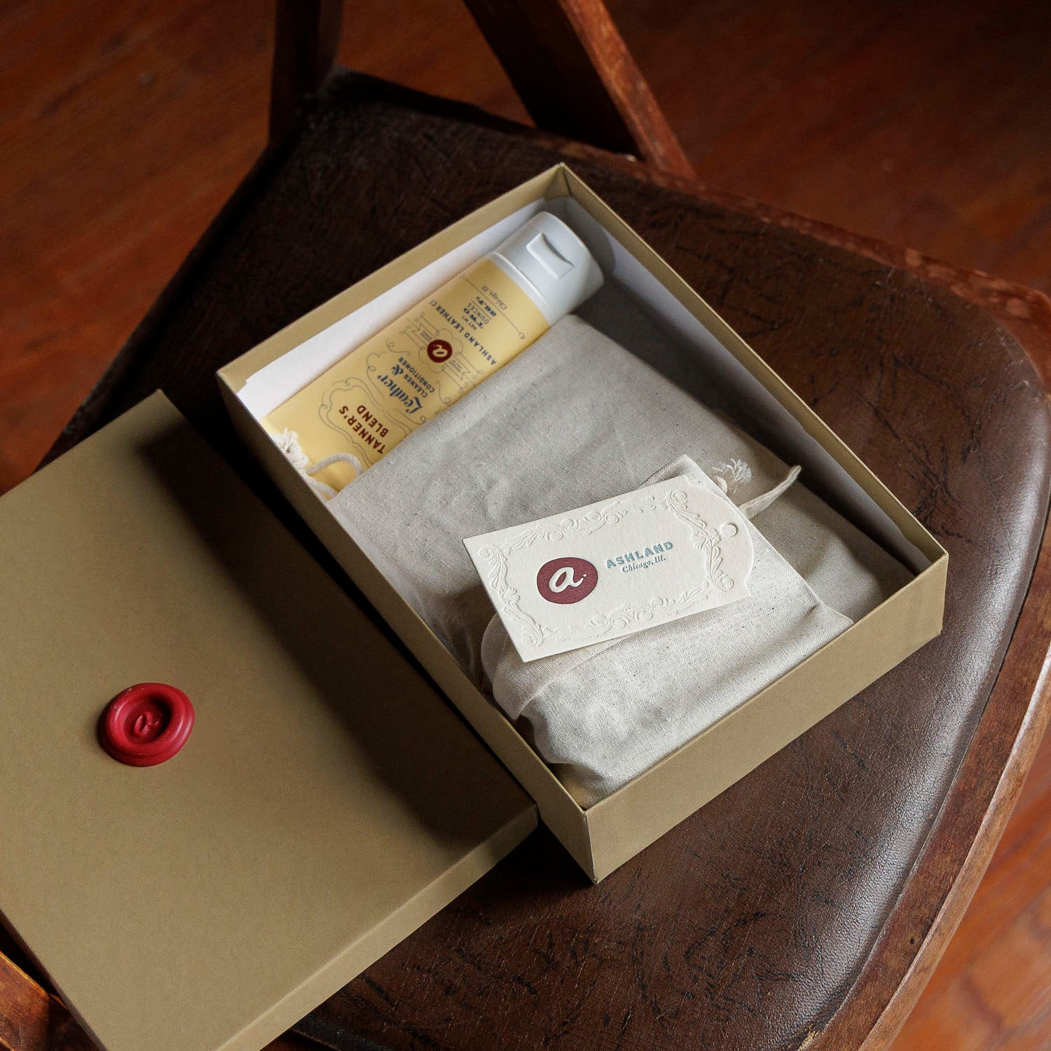 Ashland Leather Mystery Box with lid off, tissue wrapped pieces, leather care cream and Ashland tag