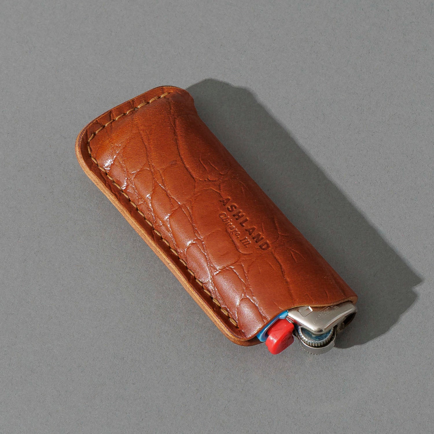 BIC Lighter and Sheath in Gator Amaretto Shell Cordovan, angled view lying flat
