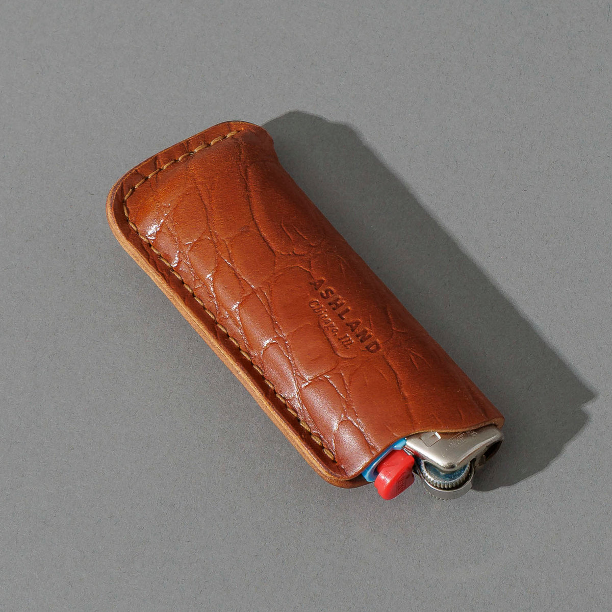 BIC Lighter and Sheath in Gator Amaretto Shell Cordovan, angled view lying flat