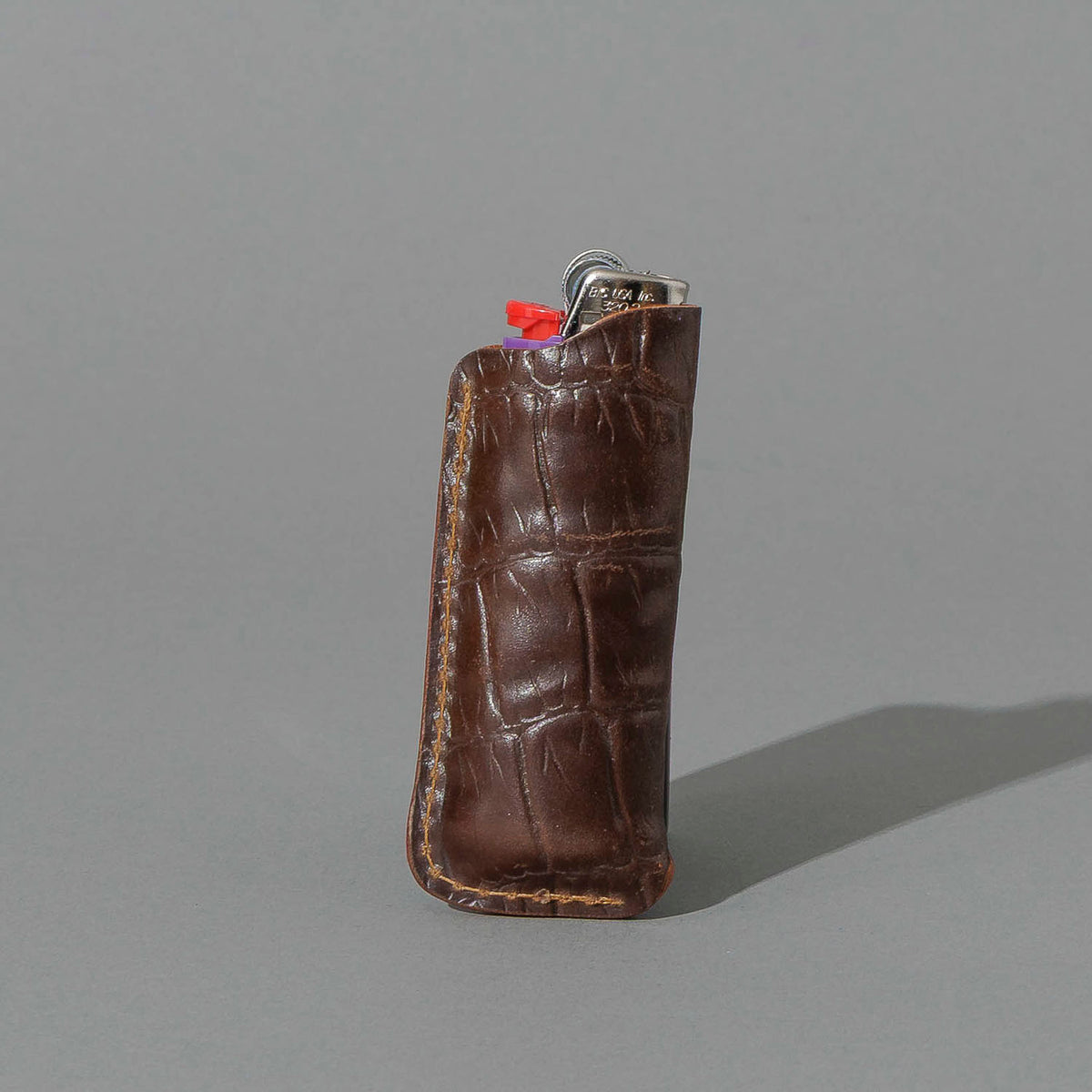 One-Off BIC Lighter and Sheath in Gator Cigar Shell Cordovan, standing upright, side angle, shot 2