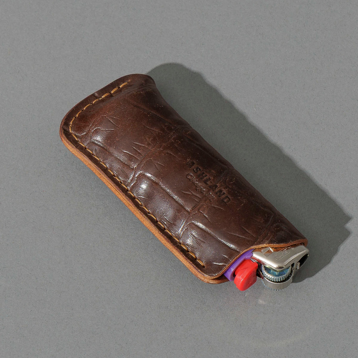 One-Off BIC Lighter and Sheath in Gator Cigar Shell Cordovan, angled view lying flat