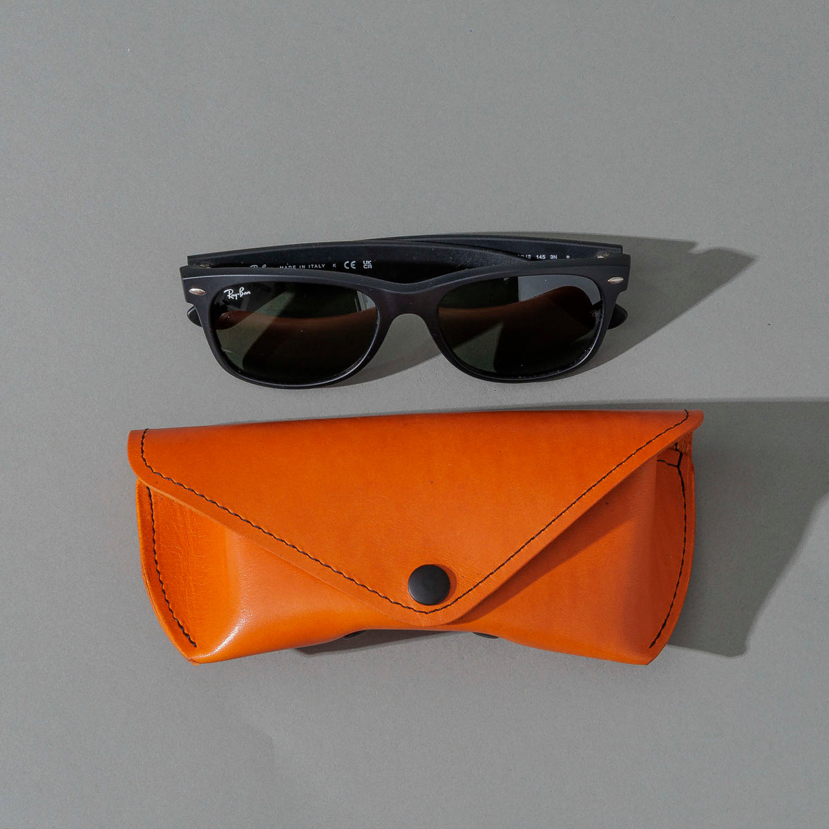 Glasses Case in Orange Latigo, next to a pair of sunglasses, shot 2