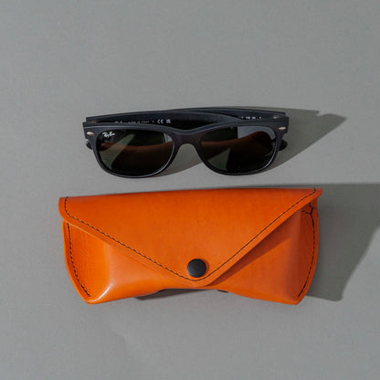 Glasses Case in Orange Latigo, next to a pair of sunglasses, shot 2