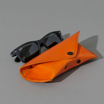 Glasses Case in Orange Latigo, next to a pair of sunglasses, shot 1