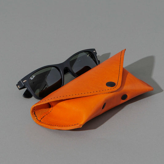 Glasses Case in Orange Latigo, next to a pair of sunglasses, shot 1