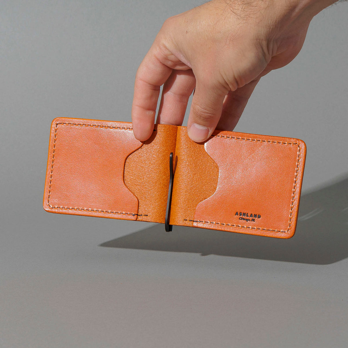 Capone Money Clip in Orange Latigo, held open in hand