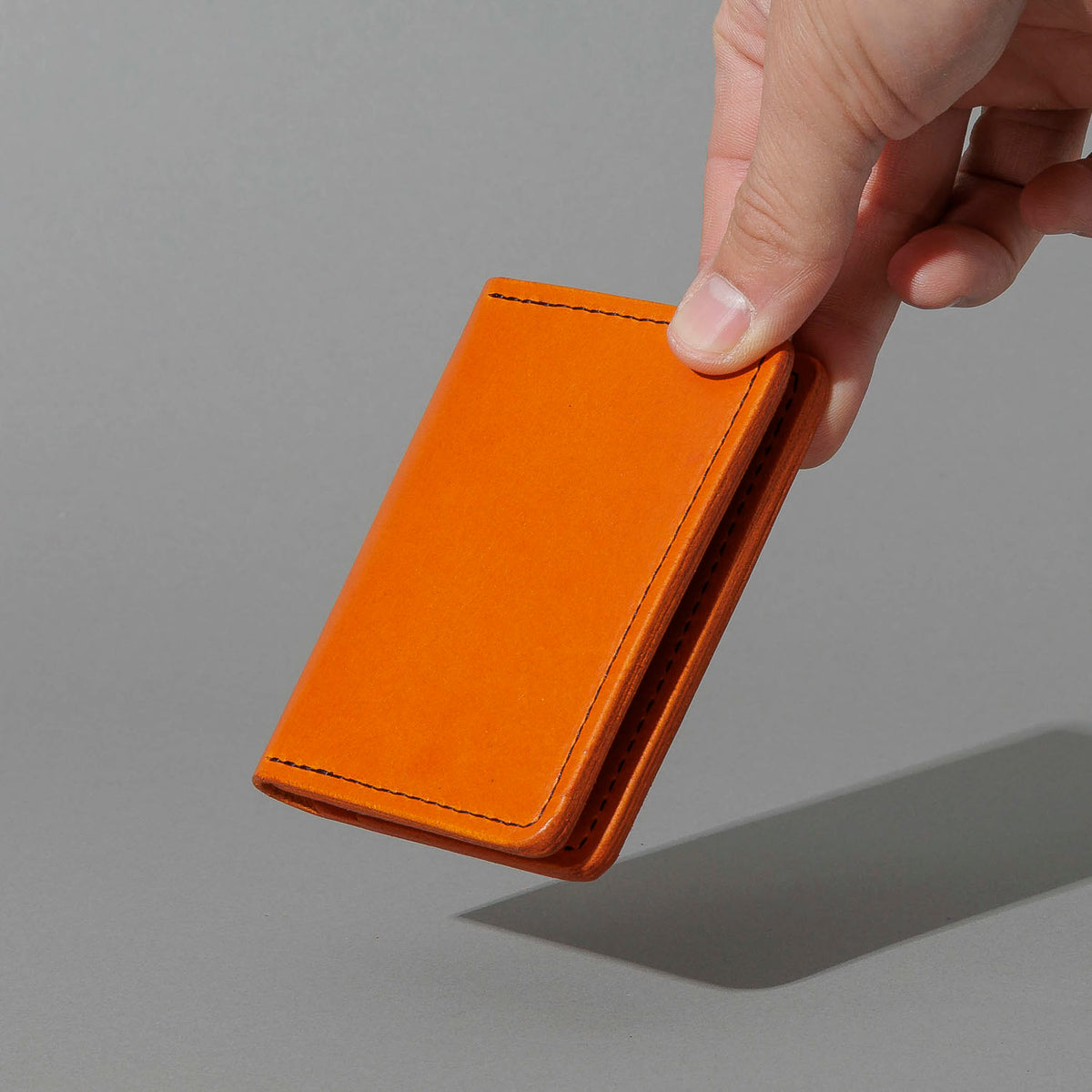 One-Off Six-Slot Bugs Moran Prototype in Orange Latigo, No Skip Stitch, held in hand, shot 2