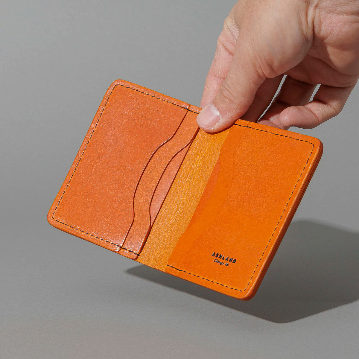One-Off Six-Slot Bugs Moran Prototype in Orange Latigo, No Skip Stitch, held open in hand