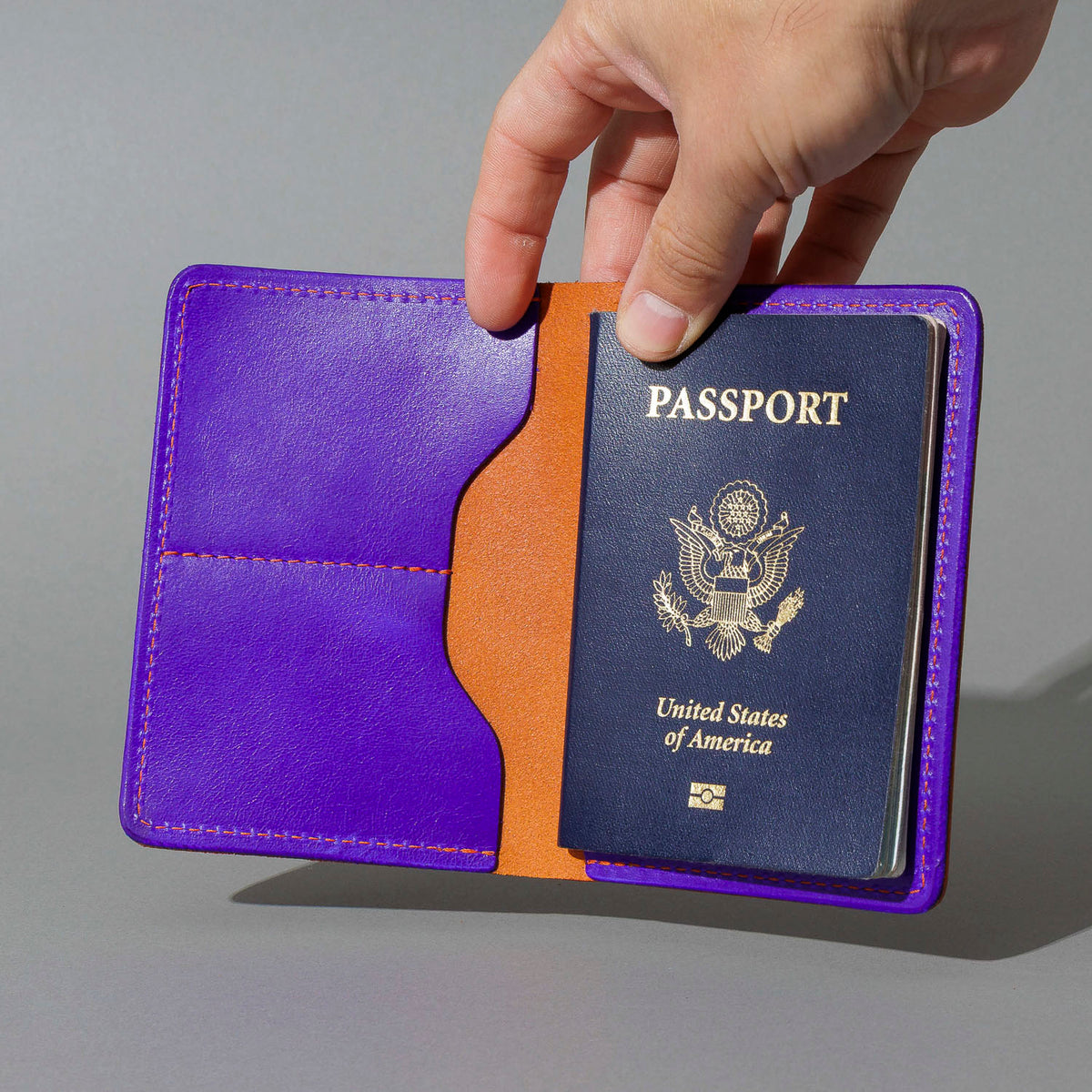 Traveler Passport Holder in Orange Latigo Exterior, Violet Latigo Interior, open with a passport inside, shot 2