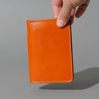 Traveler Passport Holder in Orange Latigo Exterior, Violet Latigo Interior, held in hand, shot 1