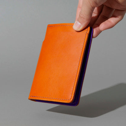 Traveler Passport Holder in Orange Latigo Exterior, Violet Latigo Interior, held in hand, shot 2