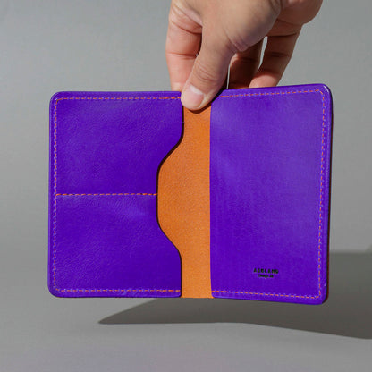 Traveler Passport Holder in Orange Latigo Exterior, Violet Latigo Interior, held open in hand