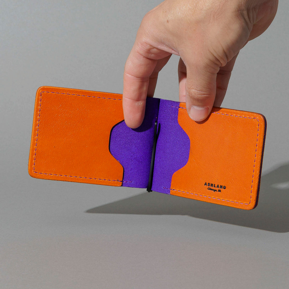 One-Off Capone Money Clip in Orange on Violet Latigo, held open in hand