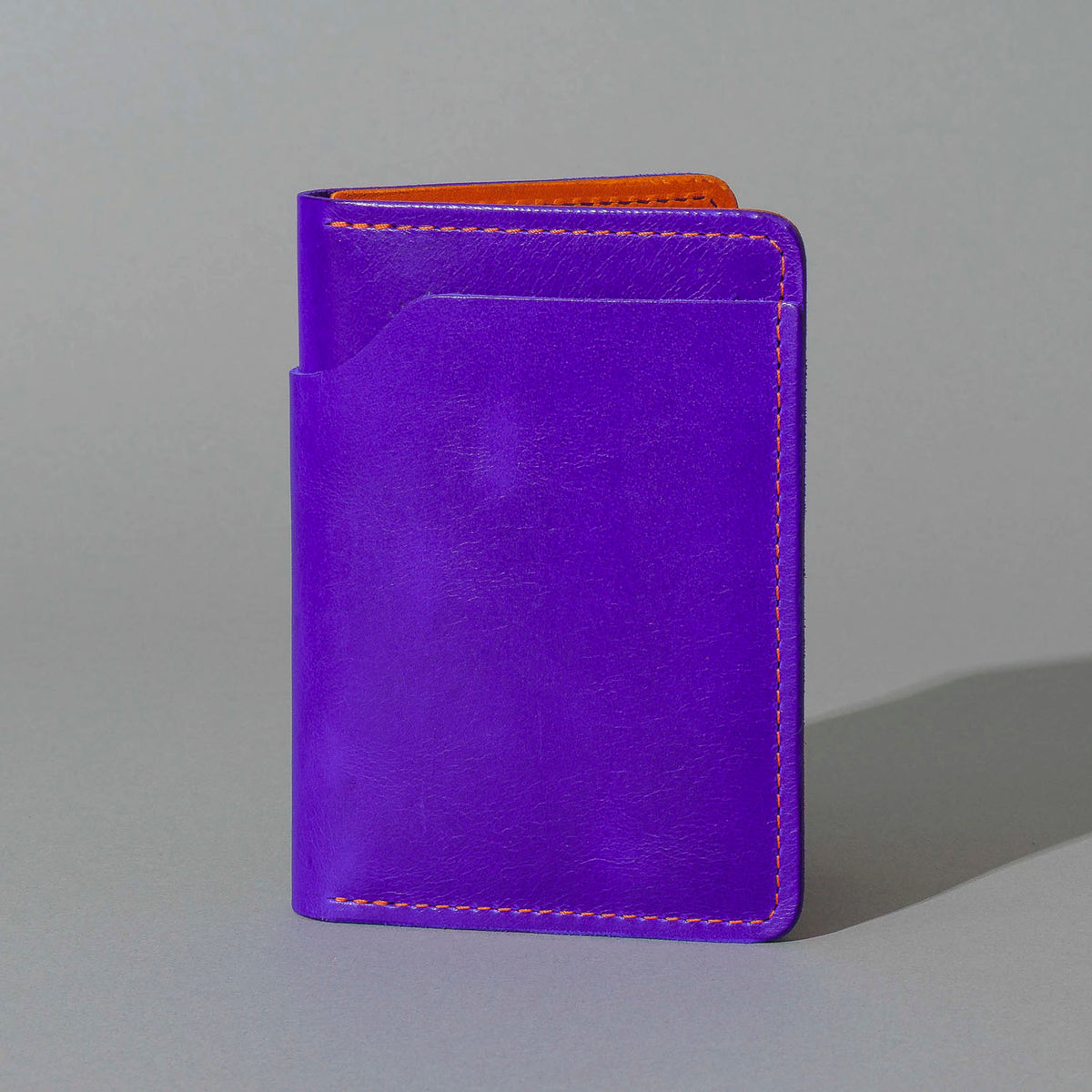 Traveler Passport Holder in Violet Latigo Exterior, Orange Latigo Interior, standing upright, side angle, shot 1