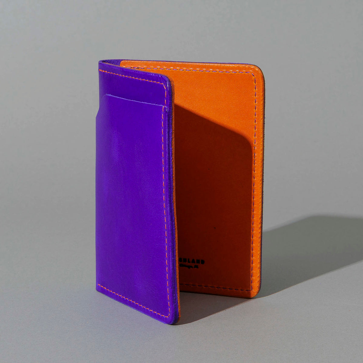 Traveler Passport Holder in Violet Latigo Exterior, Orange Latigo Interior, standing upright, side angle, shot 2