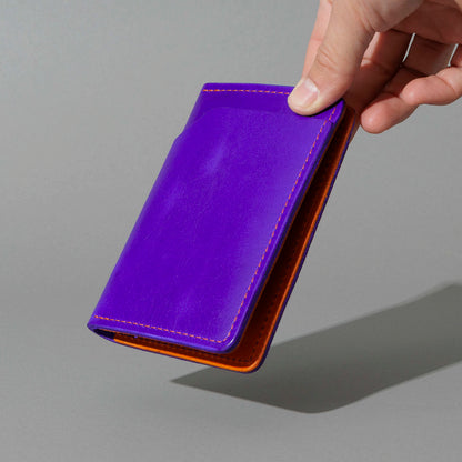 Traveler Passport Holder in Violet Latigo Exterior, Orange Latigo Interior, held in hand, shot 2