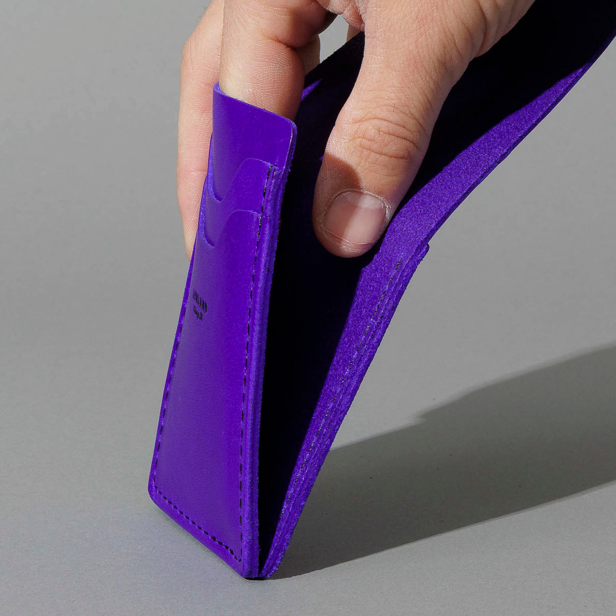 Lucky Wallet in Violet Latigo, held open in hand