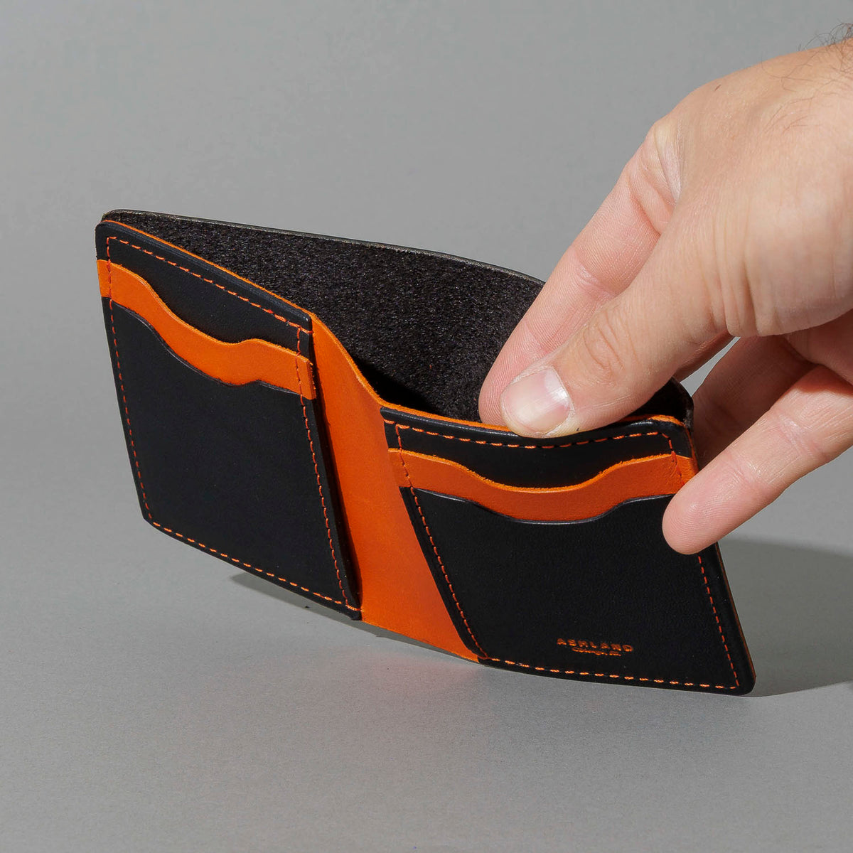 Tall Vertical Tony in Black Dublin with Orange Accents, held open in hand, shot 2